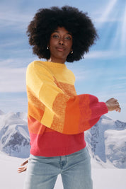 A model wearing the Valenza Jumper in colour Sunrise, from the front, showing the whole outfit