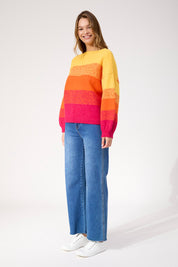 A model wearing the Valenza Jumper in colour Sunrise, from the front, showing the whole outfit