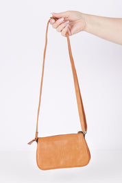 A model wearing the Brag Leather Crossbody Bag in colour Tan, from the front, showing the whole outfit