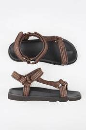 Model Genericm wearing size sample of the Reva Sandal - Chocolate in colour Chocolate, from an angle