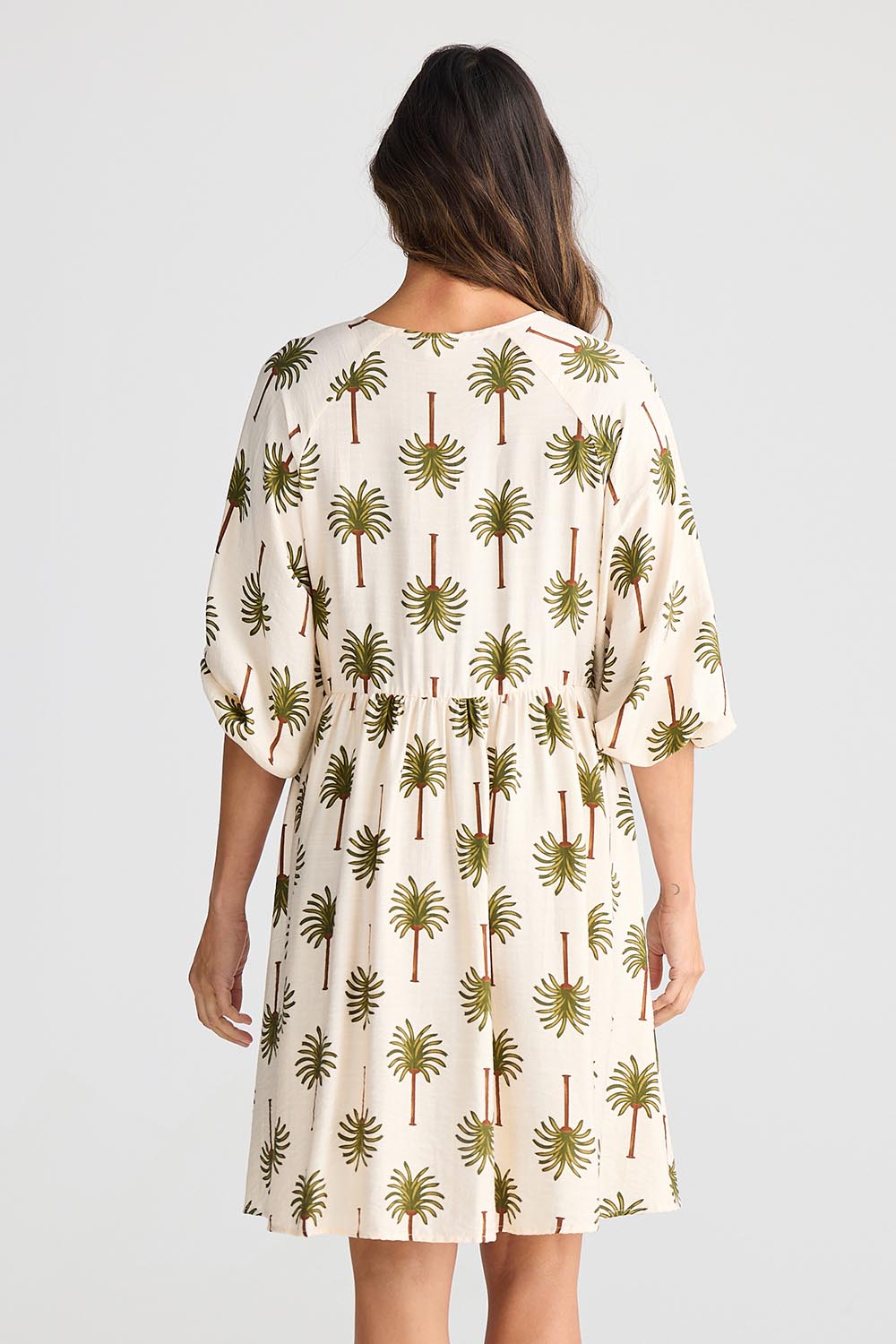 A model wearing the Alfina Dress in colour Ivorypalm, from the back