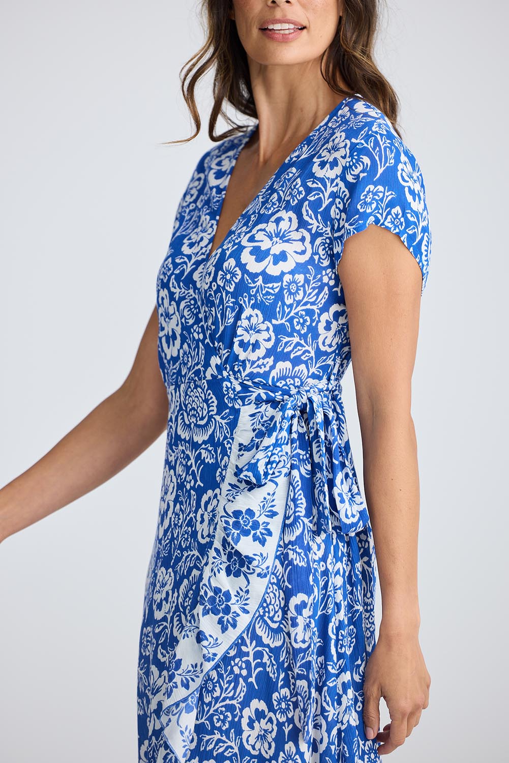 A model wearing the Lotus Wrap Dress in colour Oceanpara (Blue), from the front, cropped image