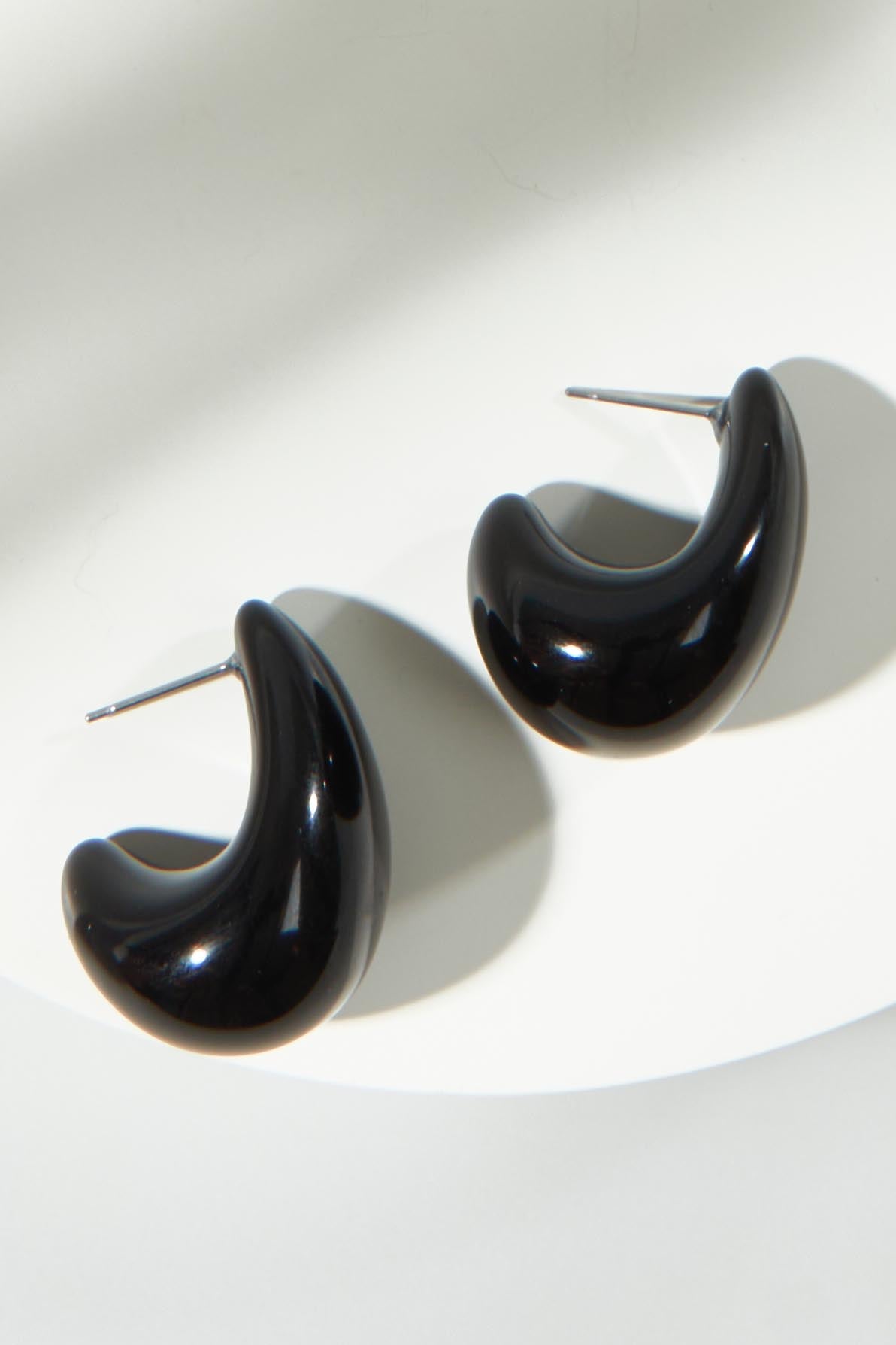 A model wearing the Gina Earrings in colour Black (Black), from the front, showing the whole outfit