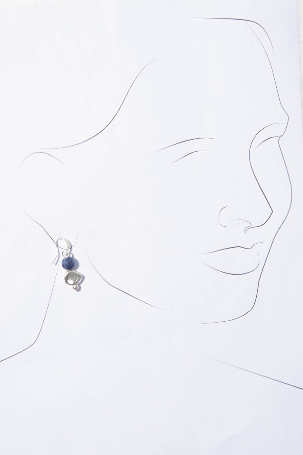 A model wearing the Binnie Earrings in colour Navysilv (Blue), from the front, showing the whole outfit