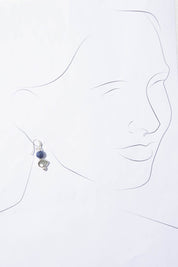 A model wearing the Binnie Earrings in colour Navysilv (Blue), from the front, showing the whole outfit