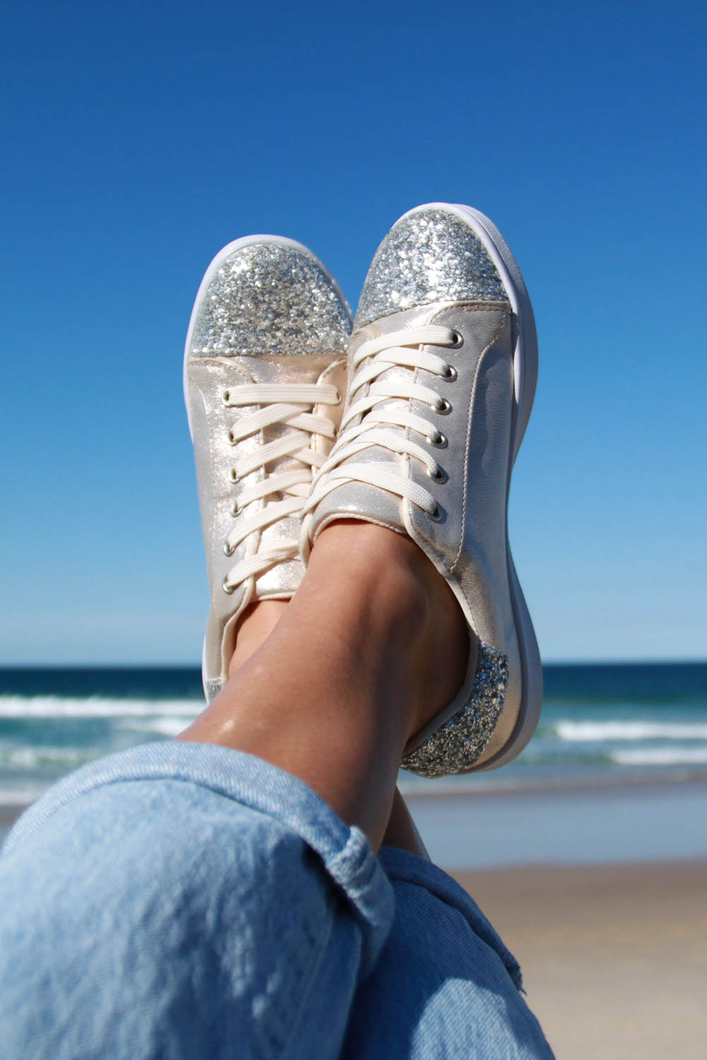 A model wearing the Stardust Sneaker in colour Champagne, from the front, cropped image