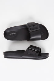 A model wearing size 7 of the Solace EVA Slide in colour Black (Black), from the front, showing the whole outfit