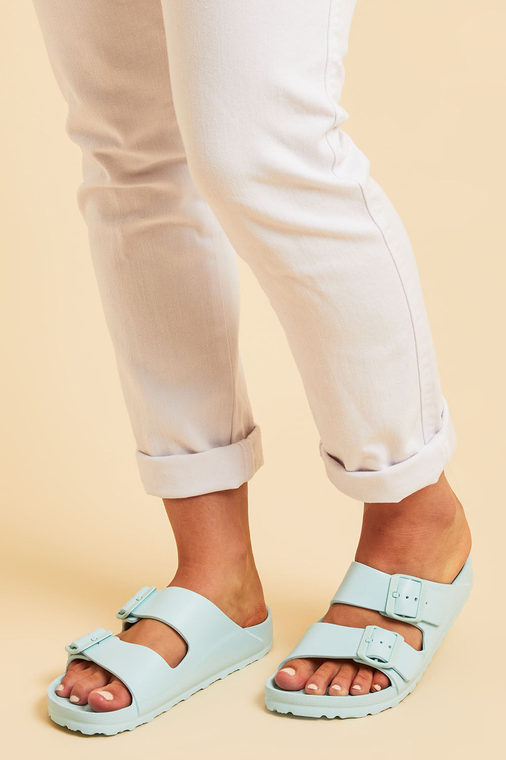 A model wearing size 7 of the Sundreamer EVA Slide in colour Aqua (Blue), from the front, cropped image