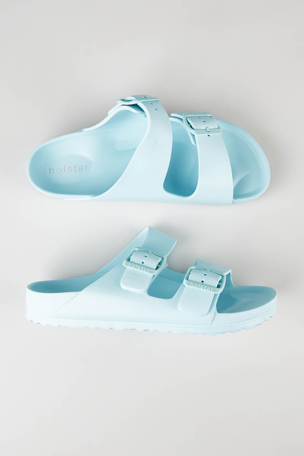 A model wearing size 7 of the Sundreamer EVA Slide in colour Aqua (Blue), from the front, showing the whole outfit