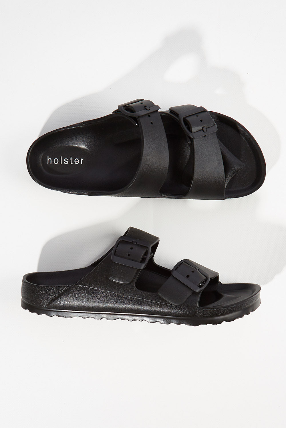 A model wearing size 6 of the Sundreamer EVA Slide in colour Black (Black), from the front, showing the whole outfit