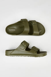 A model wearing size 7 of the Sundreamer EVA Slide in colour Khaki (Green), from the front, showing the whole outfit