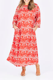 Model Natalia wearing size L of the Carabou Dress in colour NemoRed (Red), from the front, cropped image