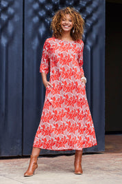 Model Summer wearing size S of the Carabou Dress in colour NemoRed (Red), from the front, showing the whole outfit