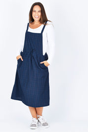 Model Stacey wearing size M of the Cara Pinafore in colour IndigoPlai (Blue), from the front, showing the whole outfit