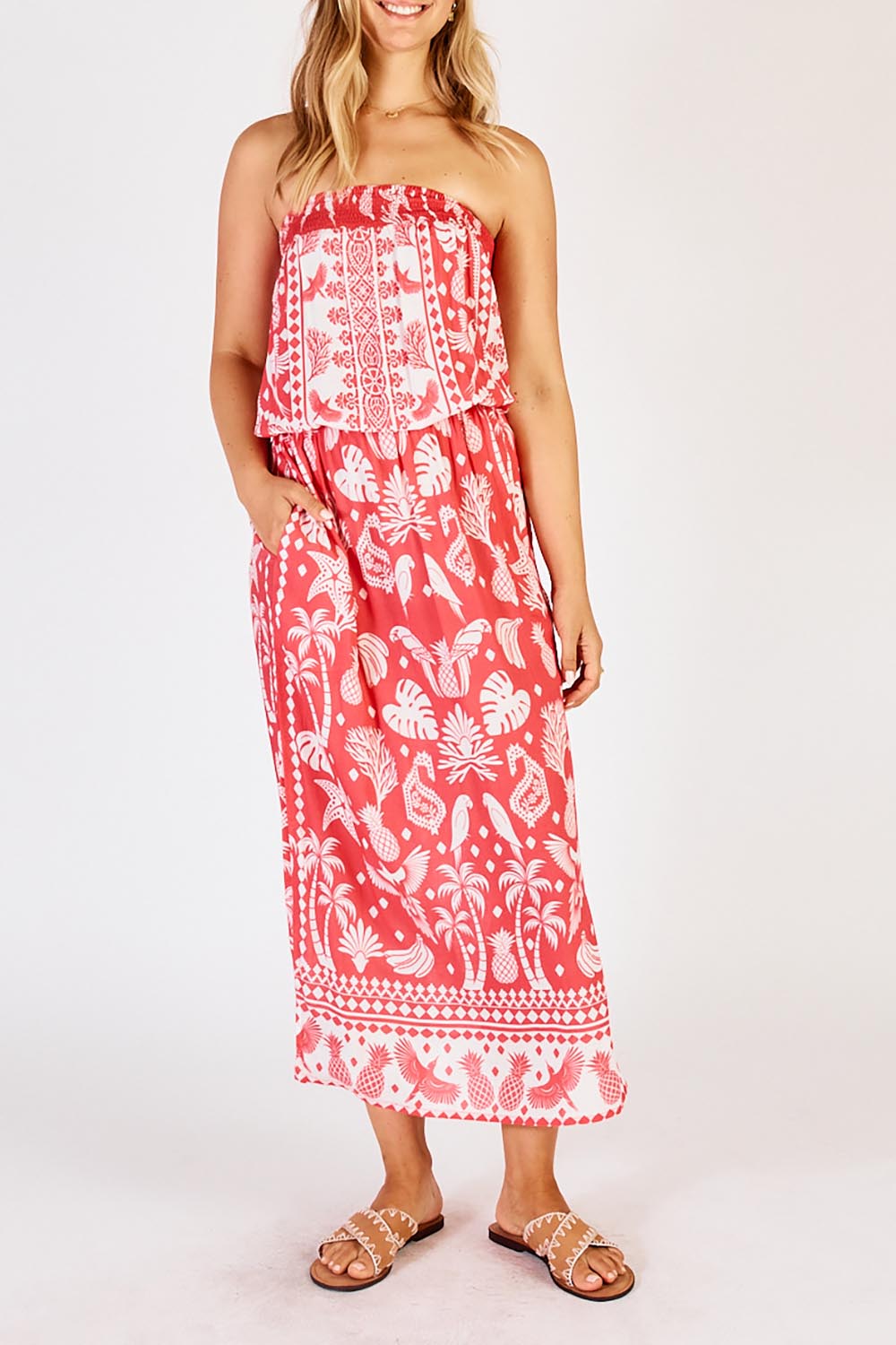 A model wearing the Agatha Strapless Dress in colour Melon (Red), from the front, cropped image