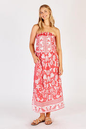 A model wearing the Agatha Strapless Dress in colour Melon (Red), from the front, showing the whole outfit