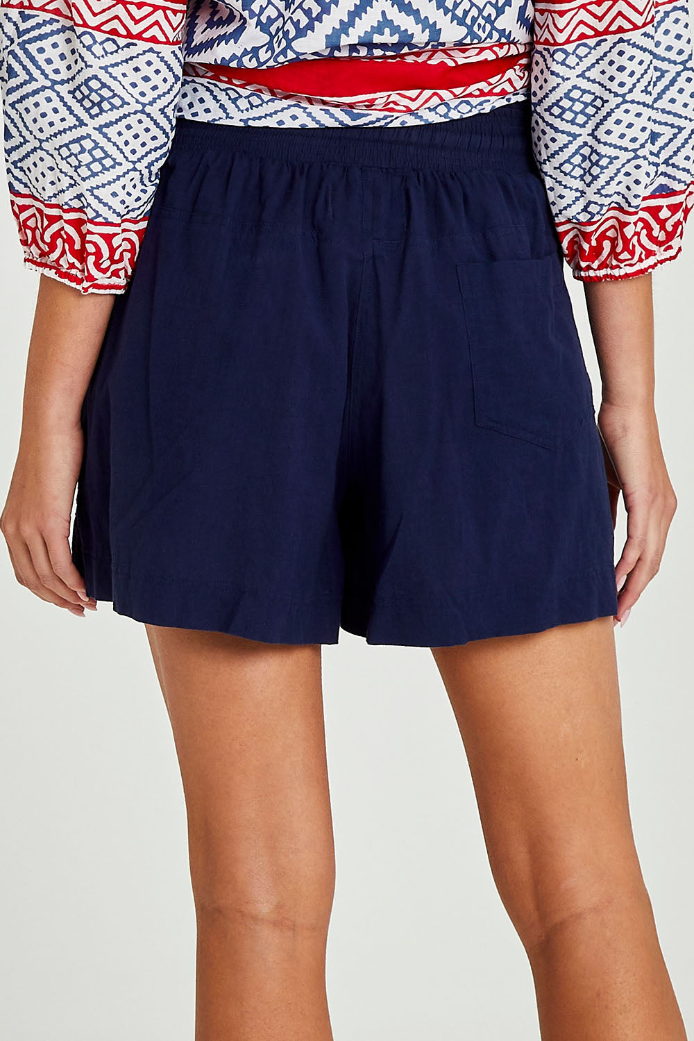 Model Madeline wearing size S of the Beach Short in colour Navy (Blue), from the back
