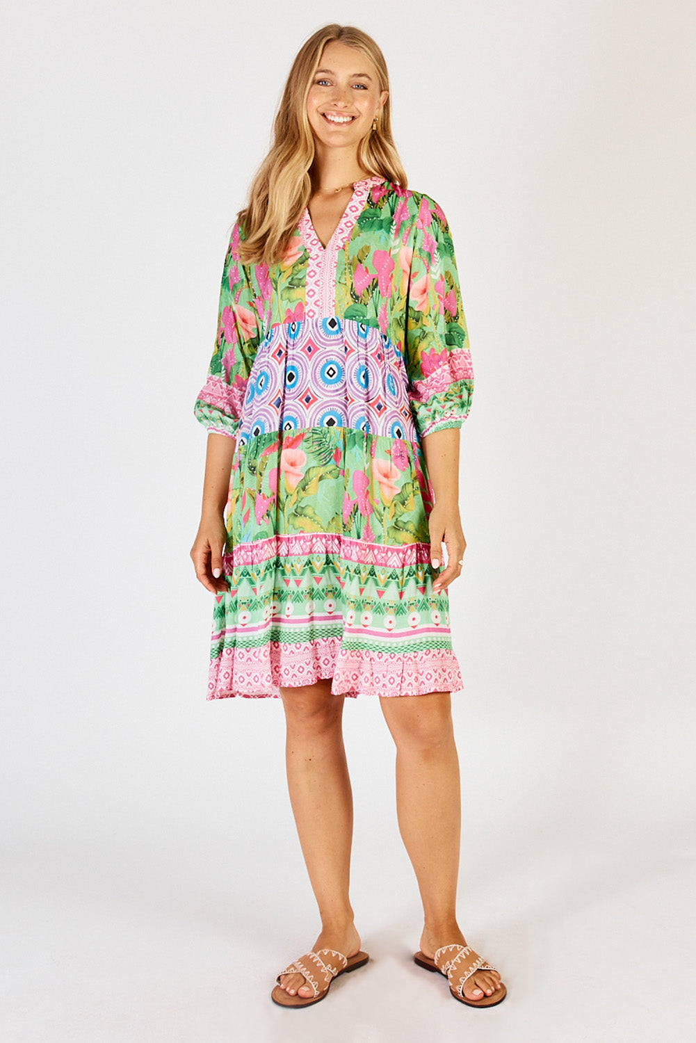 A model wearing the Ilaria Dress in colour Melon (Green), from the front, showing the whole outfit