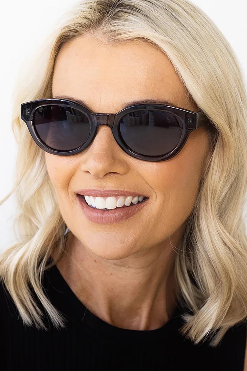 A model wearing the Faith Sunglasses in colour Black (Black), from the front, cropped image