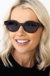 A model wearing the Faith Sunglasses in colour Black (Black), from the front, cropped image
