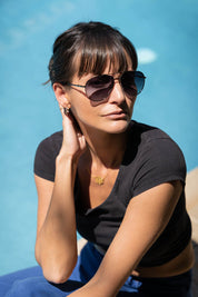 A model wearing the Mara Sunglasses in colour Black (Black), from the front, showing the whole outfit