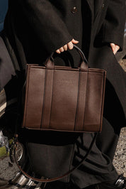 A model wearing the Manhattan Tote Bag in colour Chocolate, from the front, showing the whole outfit