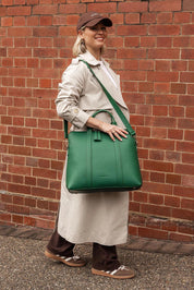 A model wearing the Rhodes Laptop Bag in colour Green (Green), from the front, showing the whole outfit