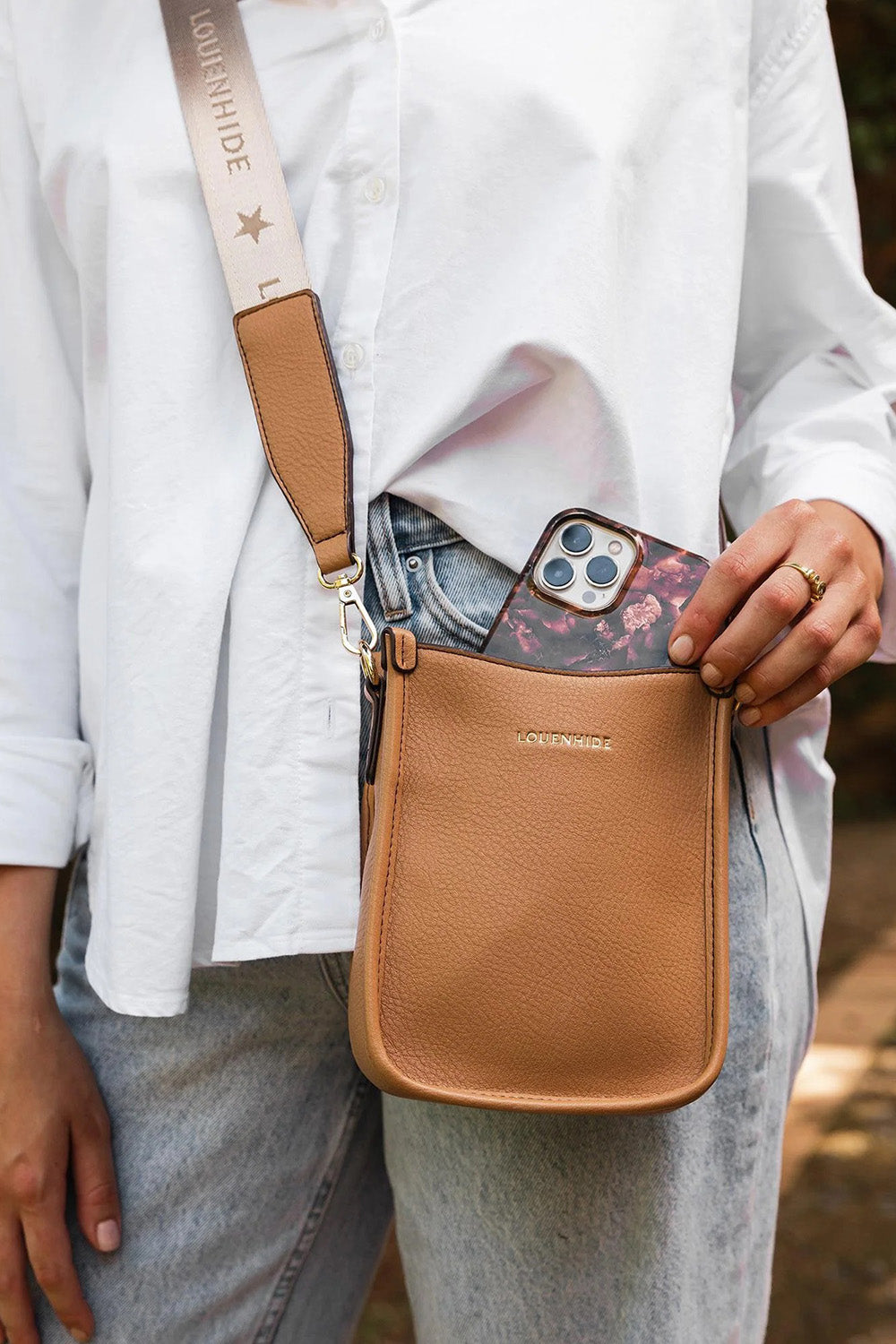 A model wearing the Parker Phone Crossbody Bag in colour Camel, from the front, showing the whole outfit