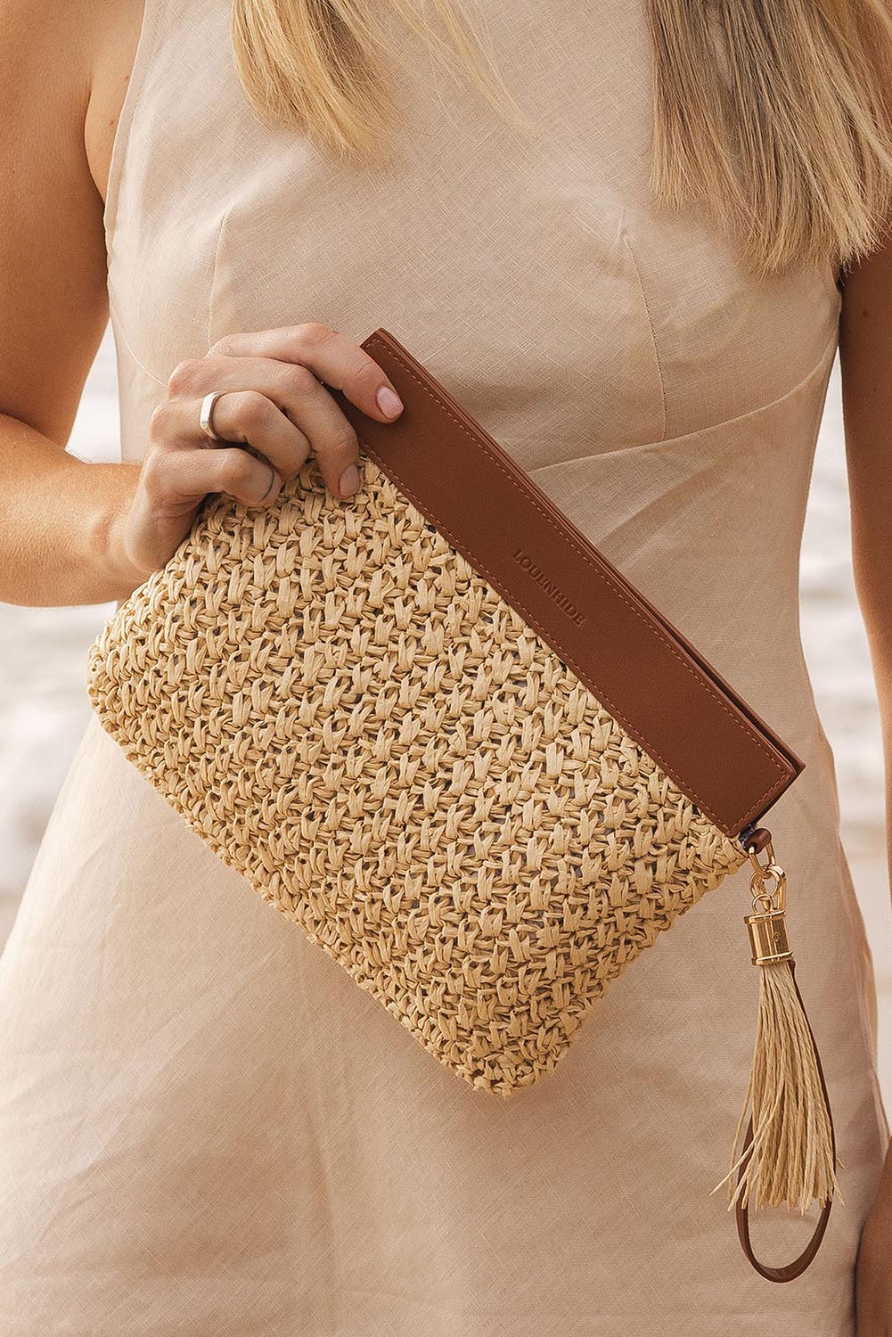 A model wearing the Fern Raffia Clutch Bag in colour Nattan, from the front, showing the whole outfit
