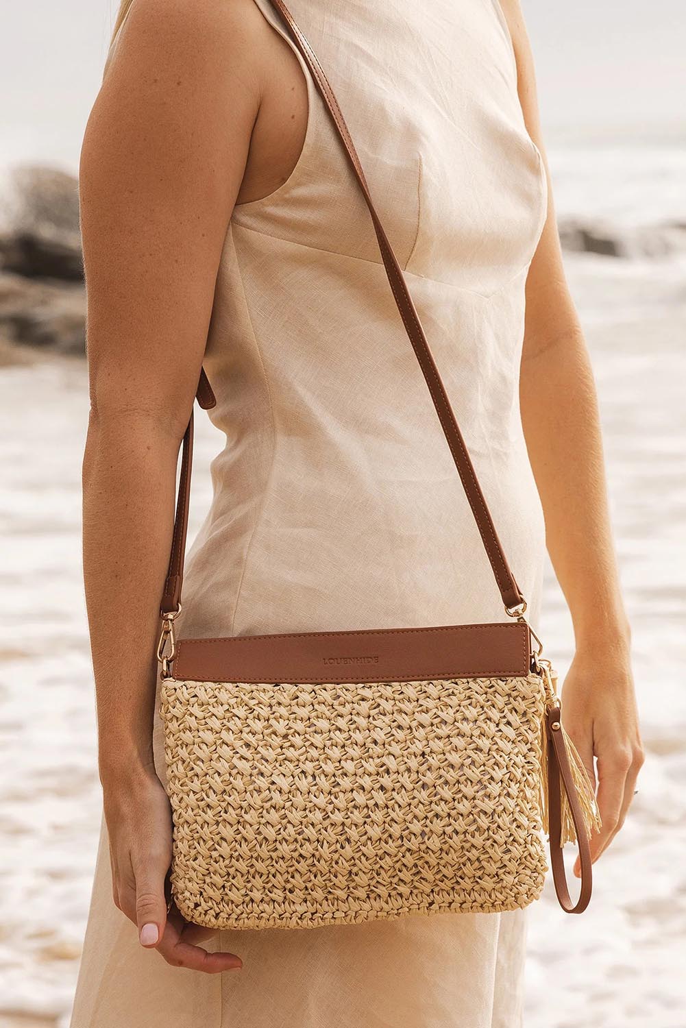 A model wearing the Fern Raffia Clutch Bag in colour Nattan, from the front, showing the whole outfit