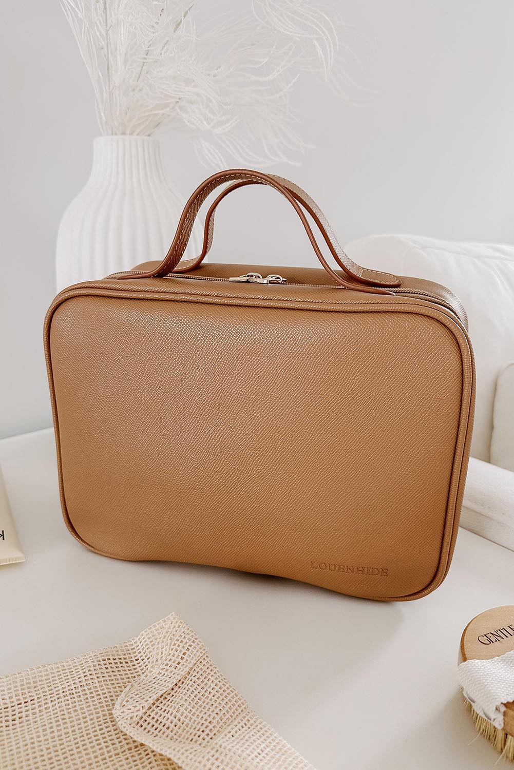 A model wearing the Baby Emma Cosmetic Case in colour Camel, from the front, showing the whole outfit
