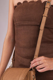 A model wearing the Shania Crossbody Bag in colour Camel, from the front, cropped image