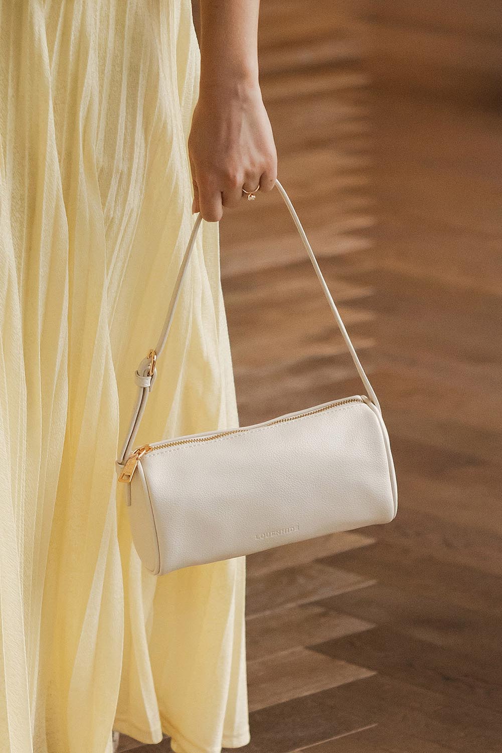 A model wearing the Serena Handbag in colour Vanilla (White), from the front, showing the whole outfit