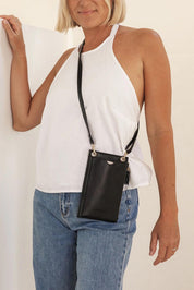 A model wearing the Suki Phone Bag in colour Black (Black), from the front, showing the whole outfit