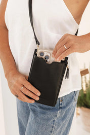 A model wearing the Suki Phone Bag in colour Black (Black), from the front, showing the whole outfit