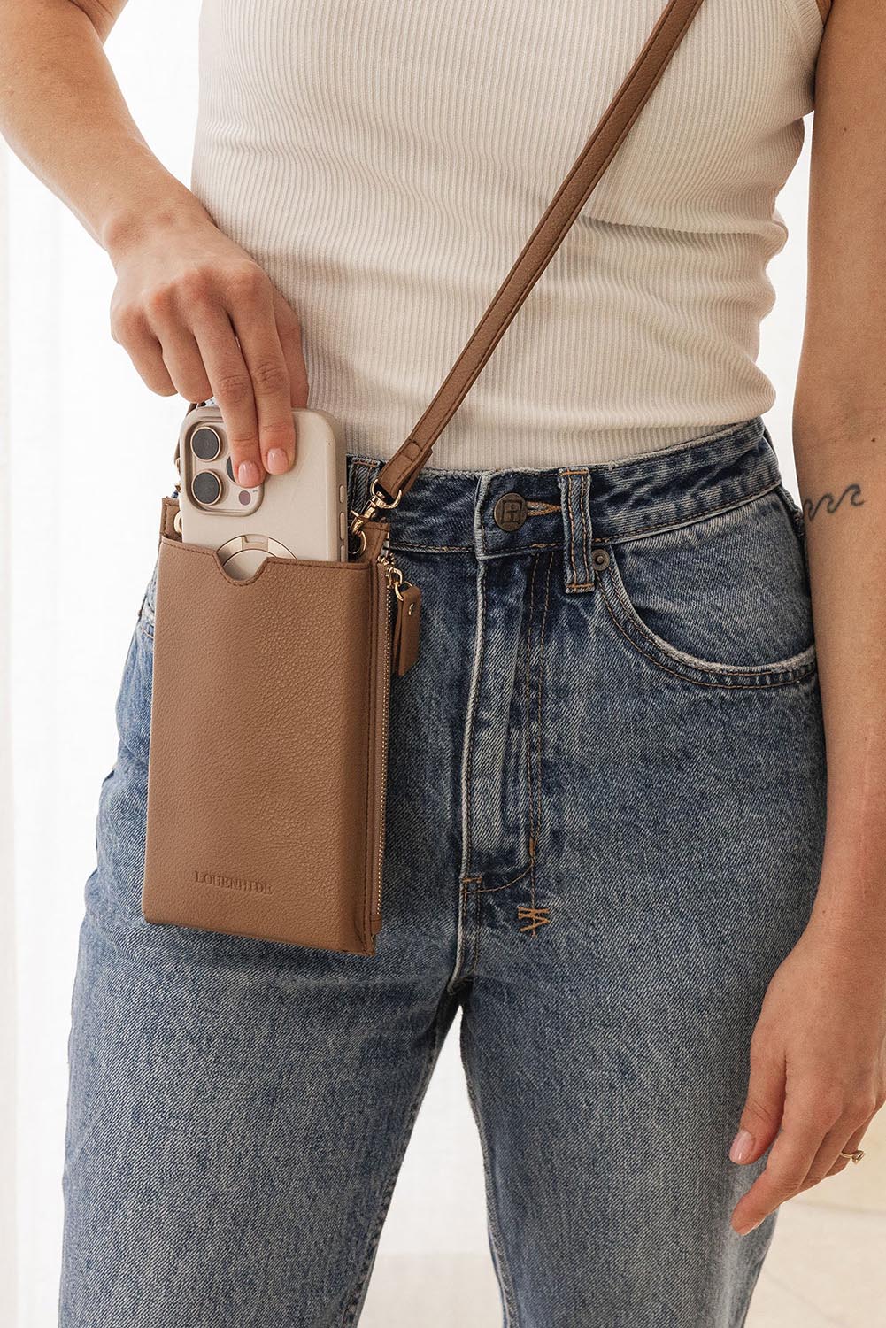 A model wearing the Suki Phone Bag in colour Caramel, from the front, showing the whole outfit