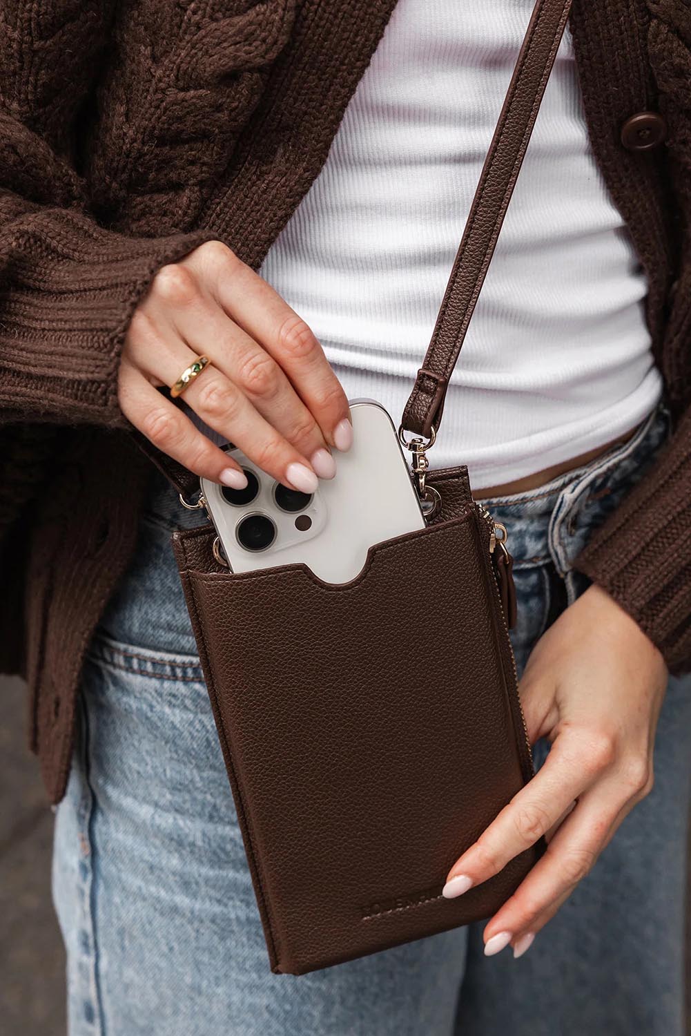 A model wearing the Suki Phone Bag in colour Chocolate, from the front, showing the whole outfit