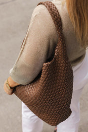 A model wearing the Gabby Woven Shoulder Bag in colour Chocolate, from the front, showing the whole outfit