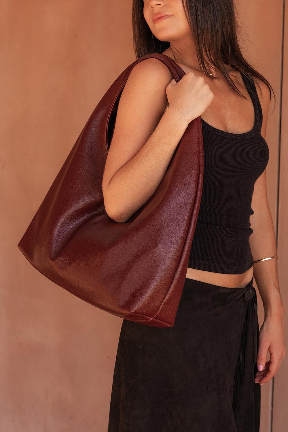 A model wearing the Monaco Shoulder Bag in colour Burgundy (Red), from the front, showing the whole outfit