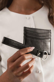 A model wearing the Ada Cardholder And Keyring in colour Blackpaten (Black), from the front, showing the whole outfit