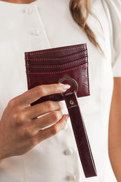 A model wearing the Ada Cardholder And Keyring in colour Burgundy (Red), from the front, showing the whole outfit