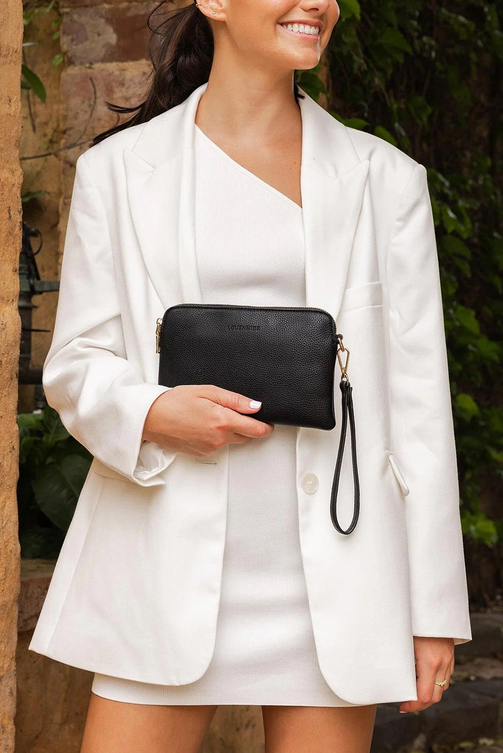 A model wearing the Poppy Clutch in colour Black (Black), from the front, showing the whole outfit