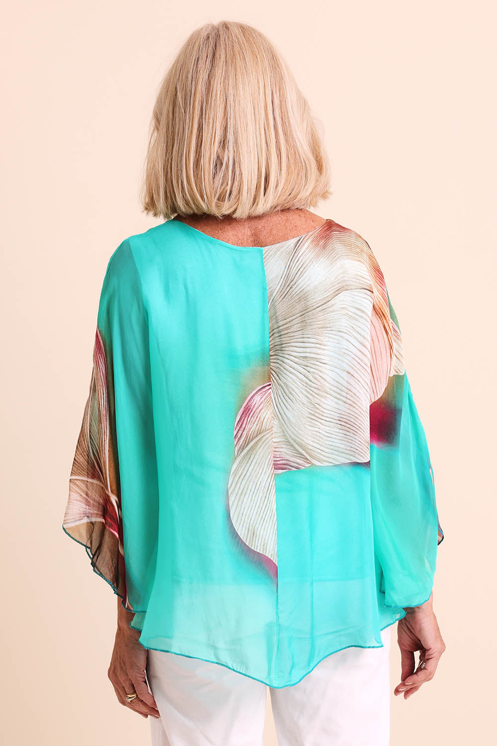 Model Sandys wearing size 10 of the Silk Blend Flounce Sleeve Top - Blueturqprint in colour Blueturqprint, from the back