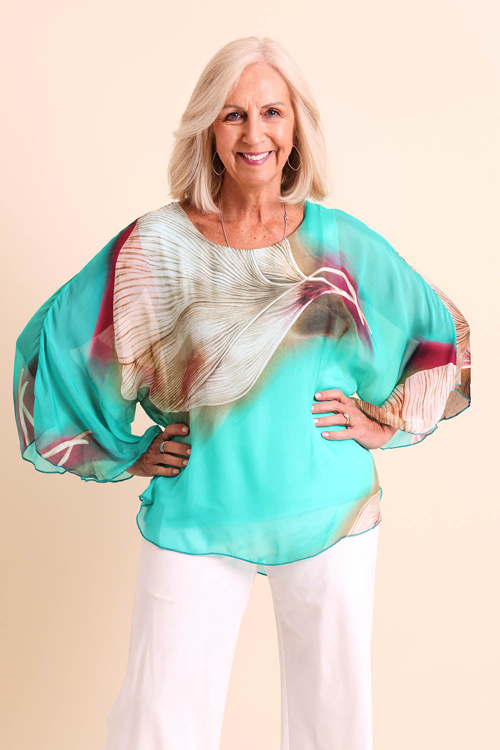 Model Sandys wearing size 10 of the Silk Blend Flounce Sleeve Top - Blueturqprint in colour Blueturqprint, in a cropped view