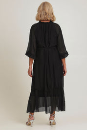 Model Sandy wearing the Long Sleeve Silk Frill Tied Neck Dress in colour Black (Black), from the back