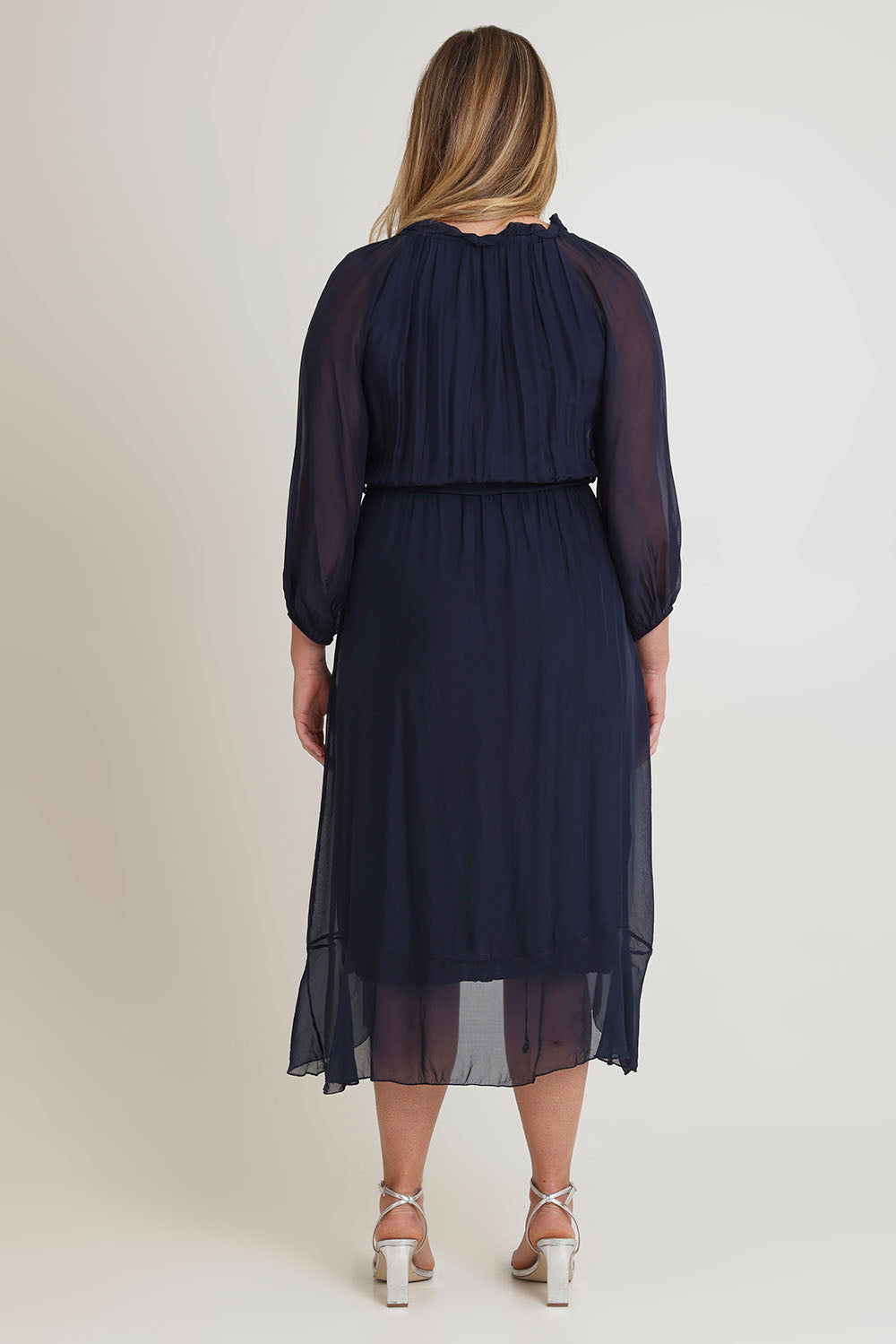 Model Chanel wearing the Long Sleeve Silk Frill Tied Neck Knee Length Dress in colour Navy (Blue), from the back