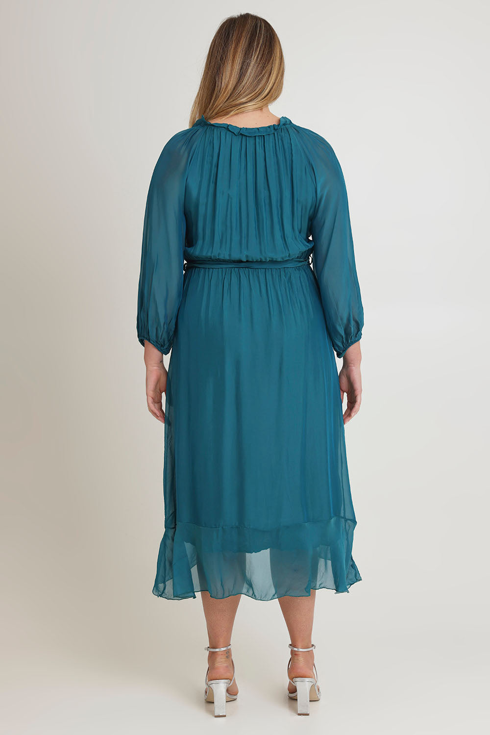 Model Chanel wearing the Long Sleeve Silk Frill Tied Neck Knee Length Dress in colour Teal (Green), from the back