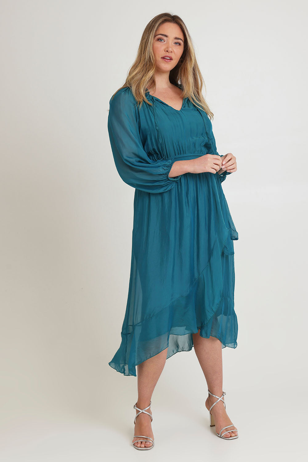 Model Chanel wearing the Long Sleeve Silk Frill Tied Neck Knee Length Dress in colour Teal (Green), from the front, showing the whole outfit