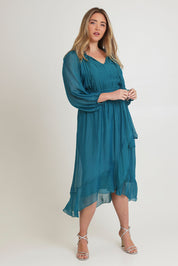 Model Chanel wearing the Long Sleeve Silk Frill Tied Neck Knee Length Dress in colour Teal (Green), from the front, showing the whole outfit