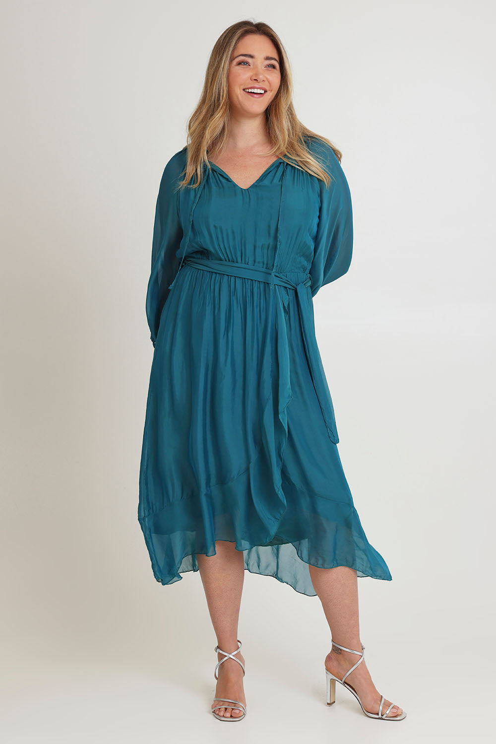 Model Chanel wearing the Long Sleeve Silk Frill Tied Neck Knee Length Dress in colour Teal (Green), from the front, showing the whole outfit